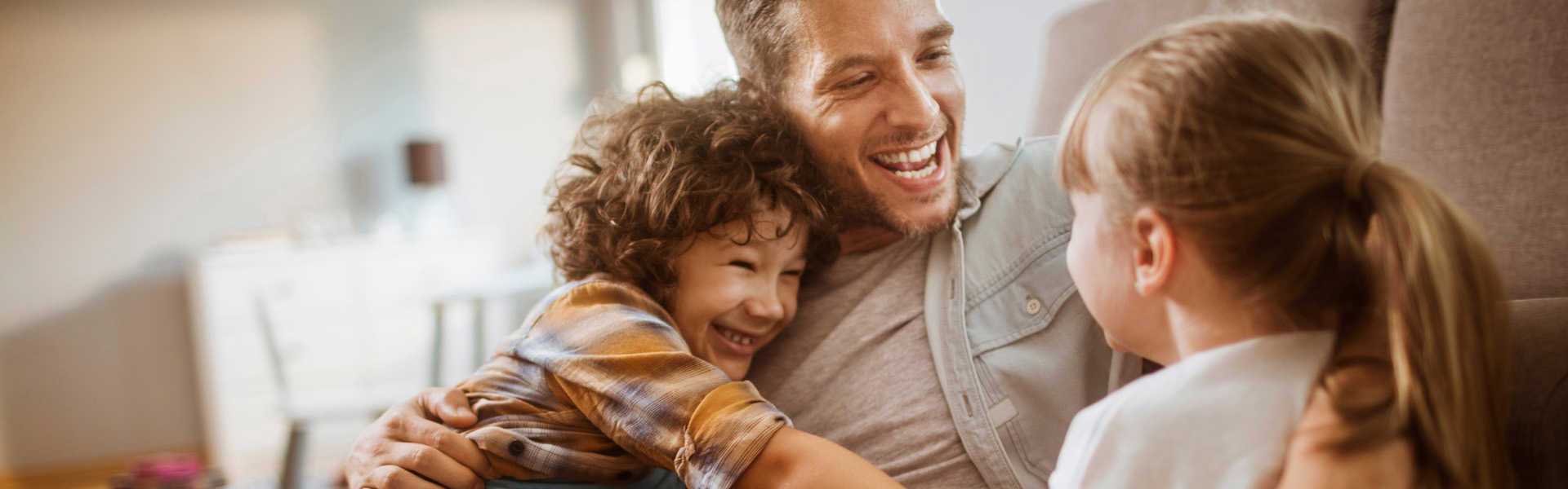 papa, zoon en dochter gezellig in de zetel die genieten van de warmtepompboilers van sinclair